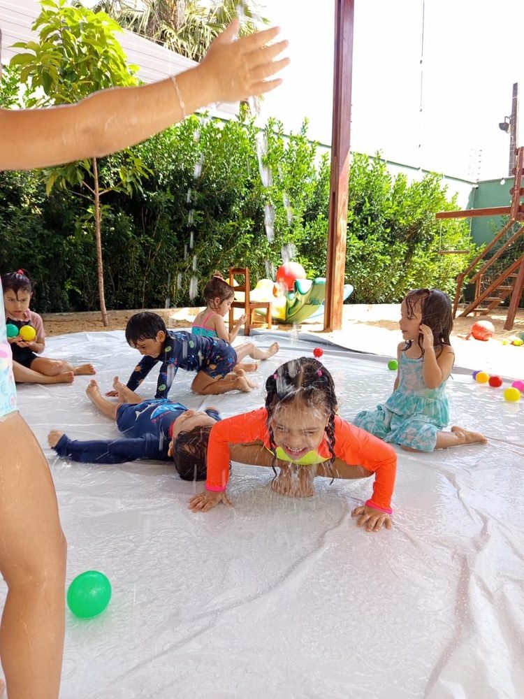 Crianças brincando com água e bolinhas coloridas em dia de brincadeira ao ar livre