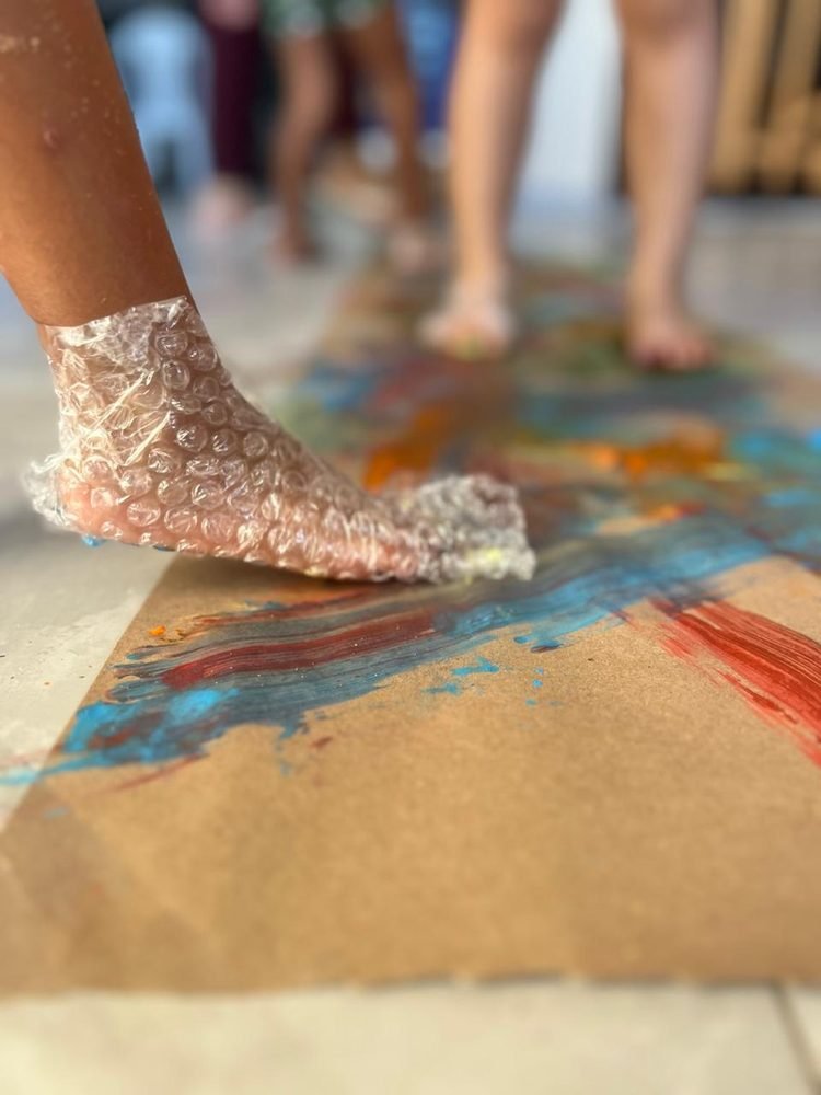 Pintura sensorial feita com os pés usando plástico bolha, atividade artística do Novo Brincar